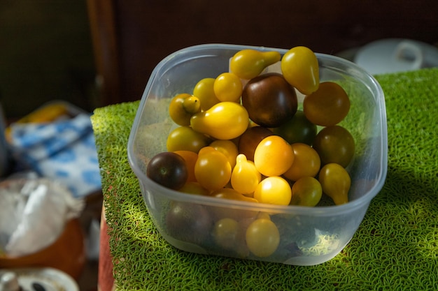 Verschillende tomaten in plastic bak op het zijaanzicht van de keukentafel