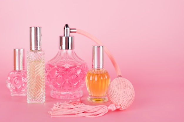 Verschillende transparante parfumflesjes op roze achtergrond