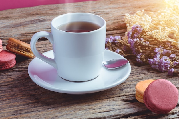 Verschillende typekleur van makarons met Kop van hete thee op Oude grunge houten achtergrond