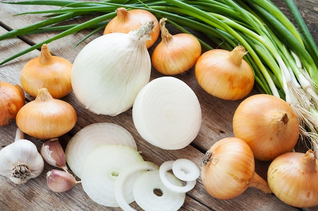 Verschillende uien en knoflookbol op houten rustieke tafel