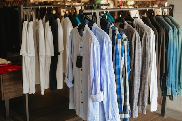 Verschillende van hemden die op kleerkleding in de winkel hangen