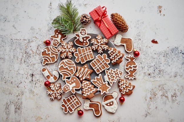 Verschillende vormen van peperkoekkerstkoekjes, gesorteerd in een cirkel en op een witte, roestige tafel geplaatst. Met kopieerruimte. Bovenaanzicht