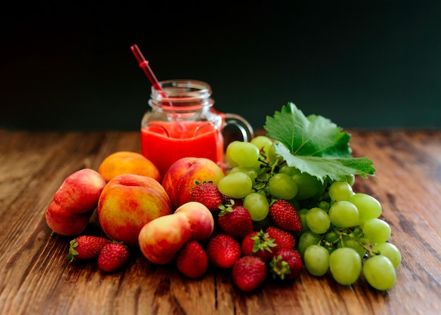 Verschillende vruchten met een smoothie op een houten tafel