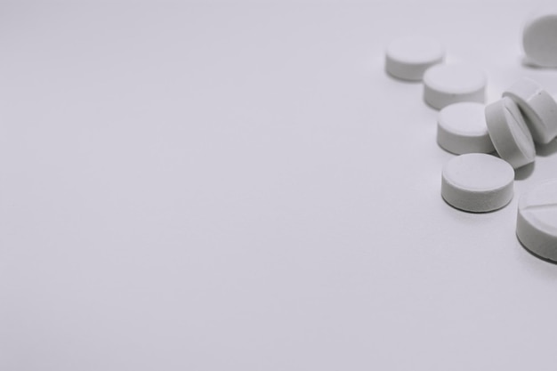 Verschillende witte pillen op een witte achtergrond in de bovenste hoek van het medische thema van de foto