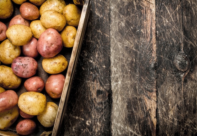 Verse aardappelen in een oude doos. Op een houten tafel.