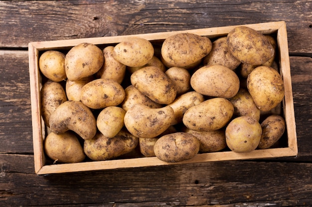 Verse aardappelen in houten kist op houten tafel, bovenaanzicht