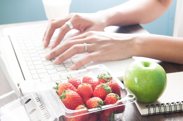 Verse aardbeien en appel met werkende vrouw