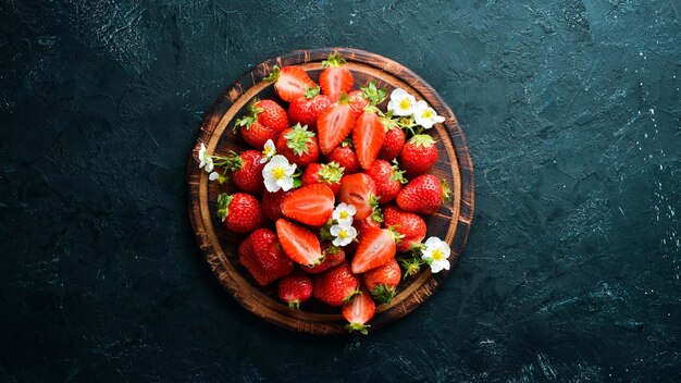 Foto verse aardbeien in een bord op een zwarte stenen achtergrond bessen bovenaanzicht vrije ruimte voor uw tekst