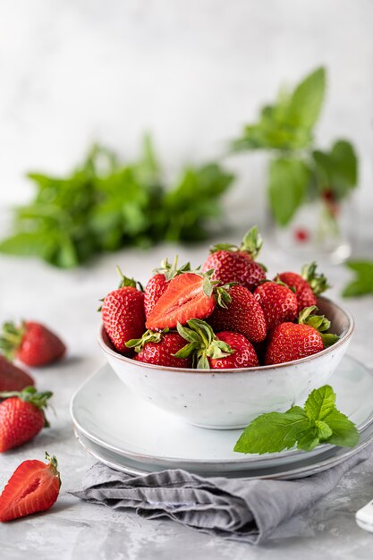 Verse aardbeien in een kom op een witte betonnen tafel.