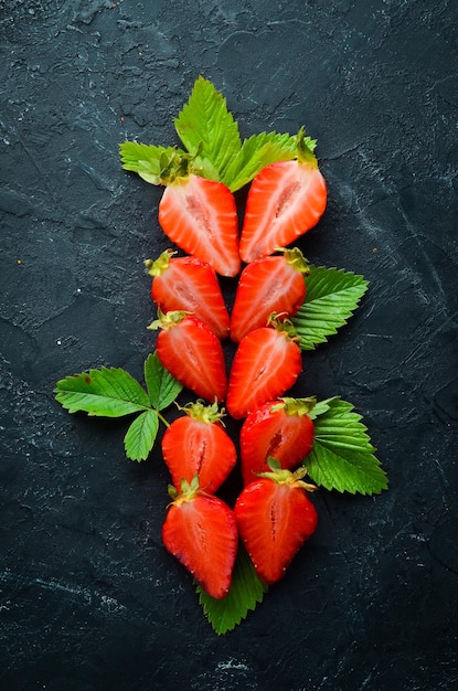 Verse aardbeien met bladeren op een zwarte stenen achtergrond Bessen Bovenaanzicht Vrije ruimte voor uw tekst