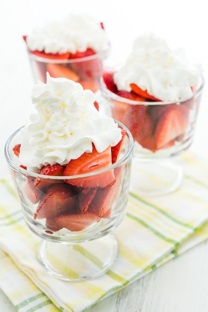 Verse aardbeien met slagroom in glazen kommen crème voor het dessert.