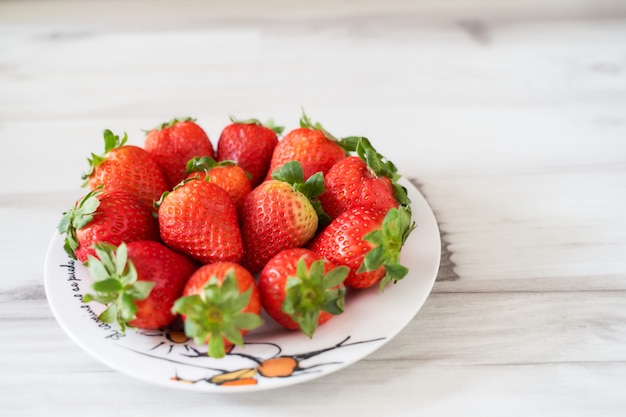 Foto verse aardbeien op een witte plaat op een zachte houten basis