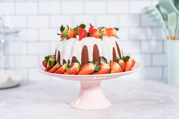 Verse aardbeien. Red velvet bundt cake met roomkaas frosting gegarneerd met verse aardbeien op een roze taart staan voor Valentijnsdag.