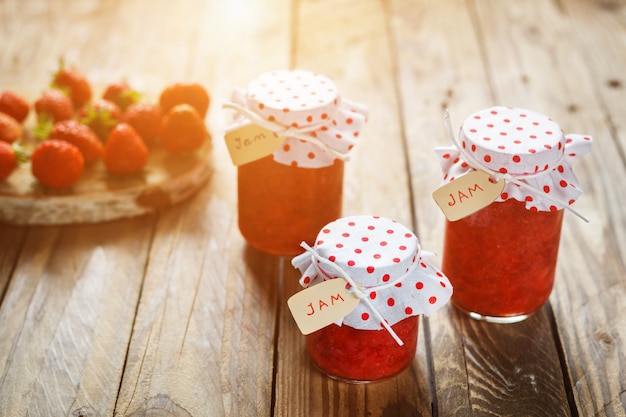 Verse aardbeien zelfgemaakte jam in pot op hout achtergrond. gezond biologisch en veganistisch eten