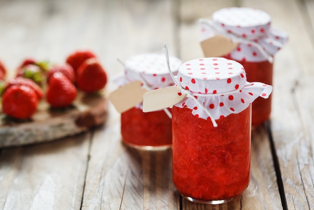 Verse aardbeien zelfgemaakte jam in pot op hout achtergrond. gezond biologisch en veganistisch eten