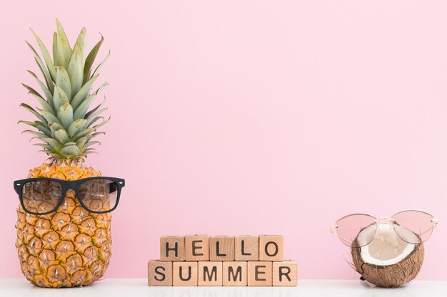 Verse ananas en kokosnoot met zonnebril op gekleurde achtergrond Hallo zomer