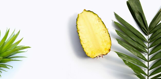 Verse ananas op tropische palmbladeren op witte achtergrond. Ruimte kopiëren