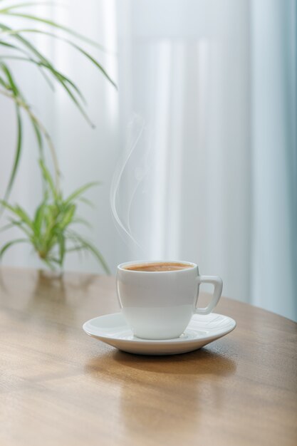 Verse aromatische koffie in een witte keramische kop op een houten tafel.