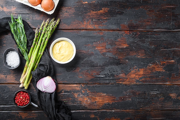 Verse asperge-eieren en Franse dressingingrediënten met dijon-mosterd, ui-dragon op donkere houten oude achtergrond, bovenaanzicht met ruimte voor tekst.