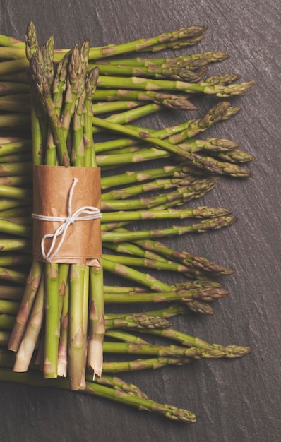 Verse asperges gebonden in een bos op een rustieke leisteenachtergrond