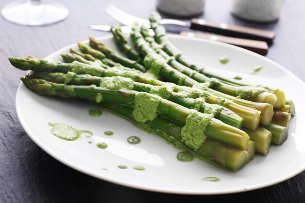 Verse aspergeschotel in groene saus op tafel close-up