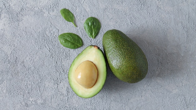 Verse avocado en segment met bladeren op grijze stenen tafel