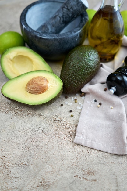 Verse avocado in tweeën gesneden en marmeren mortel op grijze betonnen tafel