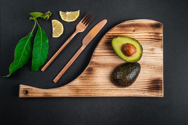 Verse avocado ligt op houten plaat op zwarte achtergrond Gezondheidsvoedsel