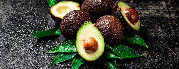 Verse avocado met bladeren op een zwarte achtergrond