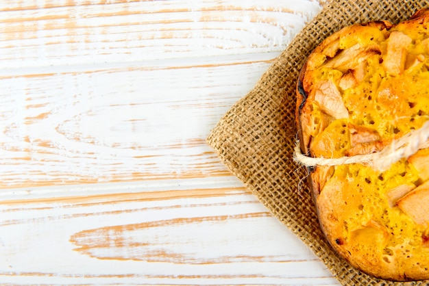 Verse bakkerij. Hoogste mening van gebakken pastei met appelen op jute op witte houten. Rustieke stijl.