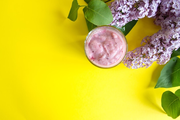 Foto verse bessen smoothie op een gele achtergrond een tak van lila en bessen smoothie kopieer de ruimte