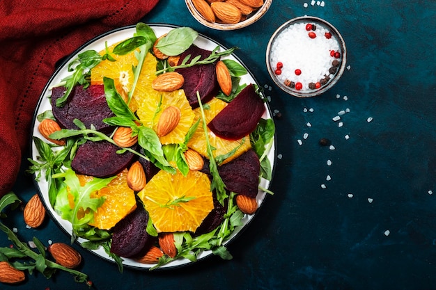 Verse bietensalade met sinaasappelrucola en amandelen op blauwe achtergrond Veganistisch gezond zomervoedsel Plat leggen Kopieerruimte