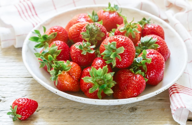 Verse biologische aardbeien in een witte plaat op een houten tafel