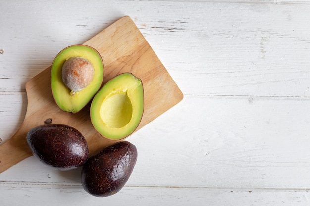 Verse biologische avocado gesneden in tweeën op witte houten tafel.