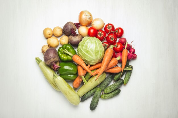 Verse biologische groenten op een witte houten oppervlak. Concept van het kopen van boerderij groenten, zorg voor gezondheid, oogst. Cirkelvorm. Landelijke stijl, Farm Fair. Plat lag, bovenaanzicht