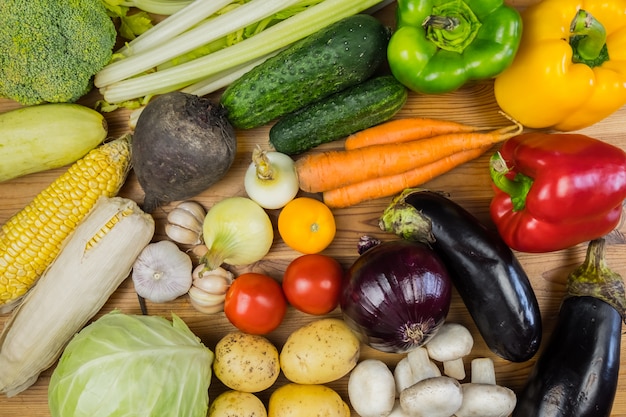 Verse biologische groenten op rustieke houten tafel, bovenaanzicht. Plat leggen van lokaal geteeld natuurlijk veganistisch eten op tafel te leggen