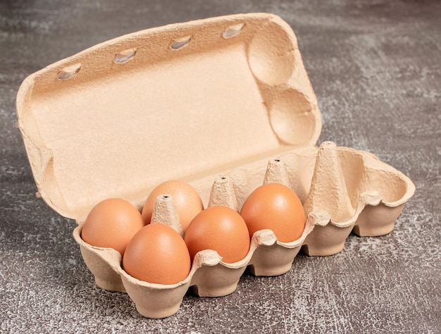 Verse biologische kippeneieren in open kartonnen verpakking of eiercontainer op bruine achtergrond