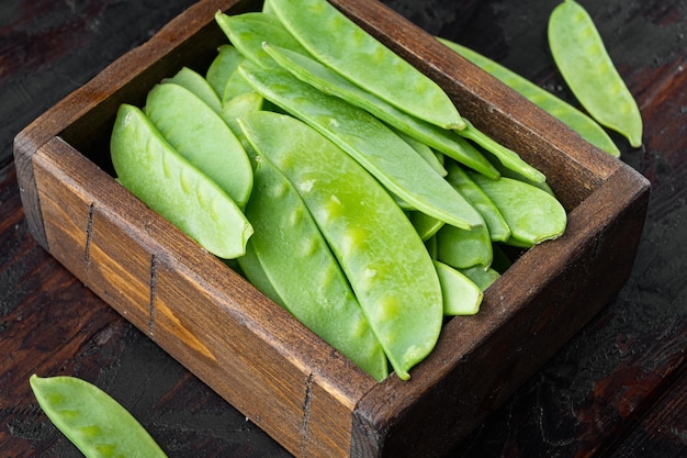 Verse biologische peultjes ook bekend als sugar snap erwt in houten kist op oude donkere houten tafel achtergrond