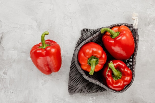 Verse biologische rijpe zoete rode paprika in milieuvriendelijke herbruikbare productzak op grijze kopieerruimte