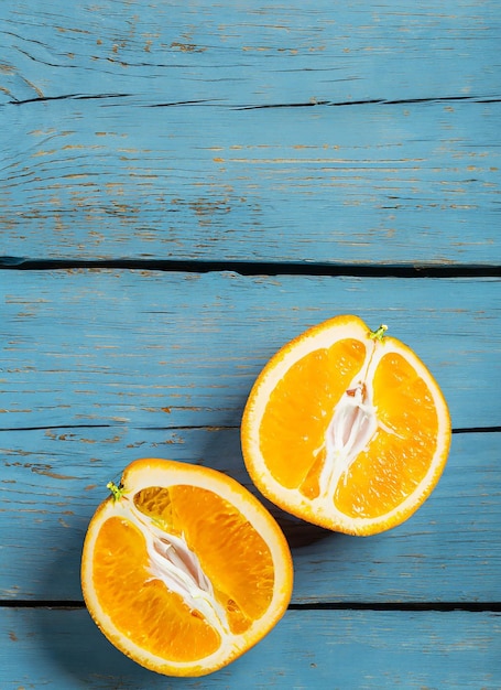 Verse biologische sinaasappels verdelen vruchten op een blauwe houten achtergrond met kopieerruimte