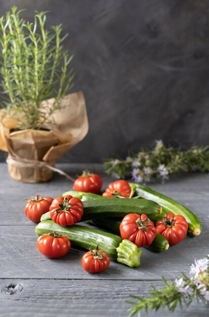 Verse biologische tomaten, courgette en rozemarijn op grijze achtergrond