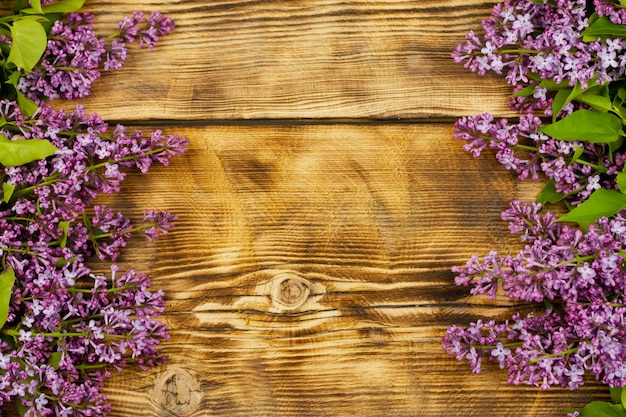 Verse bloemen met twijgen en groene lila bladeren liggen op een oude geperste houten tafel