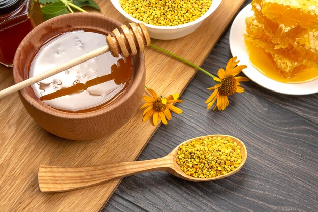 Verse bloemenhoning van verschillende soorten stuifmeel en honingraat met lepels op een houten ondergrond Biologische vitamine Health Food