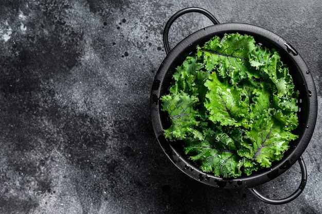 Verse boerenkoolsalade in een vergiet. Vegetarisch eten. Zwarte ruimte. Bovenaanzicht. Kopieer ruimte