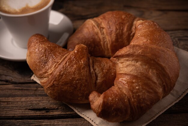 Verse boterachtige croissants met koffie op rustieke houten tafel close-up