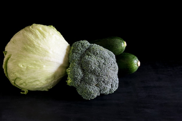 Verse broccoli en courgettegroene salade op een zwarte lijst, rustieke stijl, donkere sleutel.