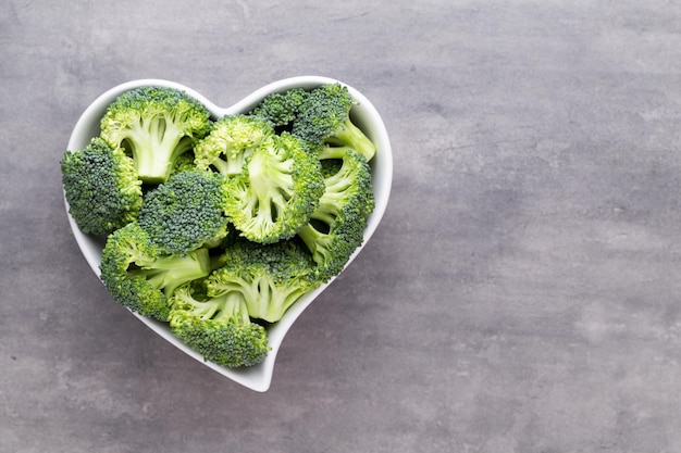 Verse broccoli in een hartvormige kom op een houten ondergrond