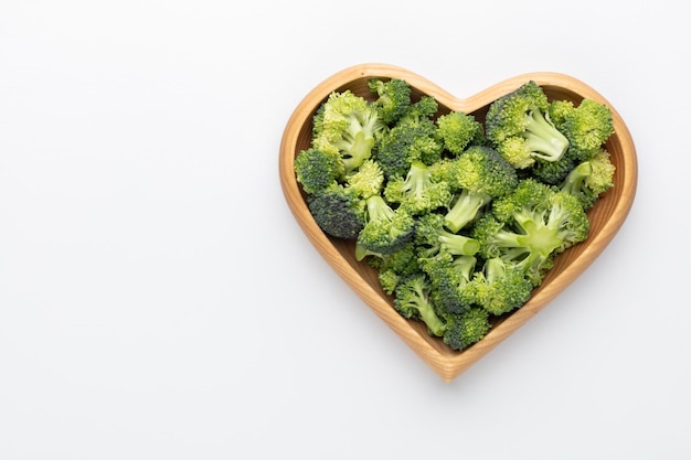 Verse broccoli in een hartvormige kom op een houten ondergrond