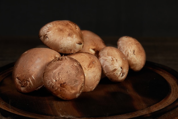 Verse bruine champignonpaddestoelen op houten lijst met donkere achtergrond