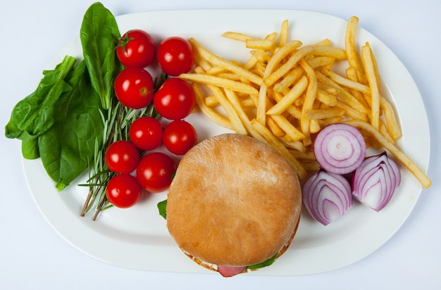 Verse burger in bord met groenten en frietjes